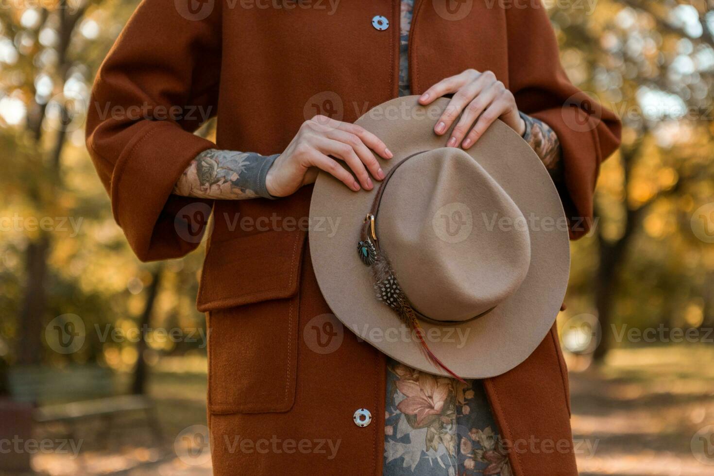 attractive stylish woman walking in park dressed in warm brown coat photo