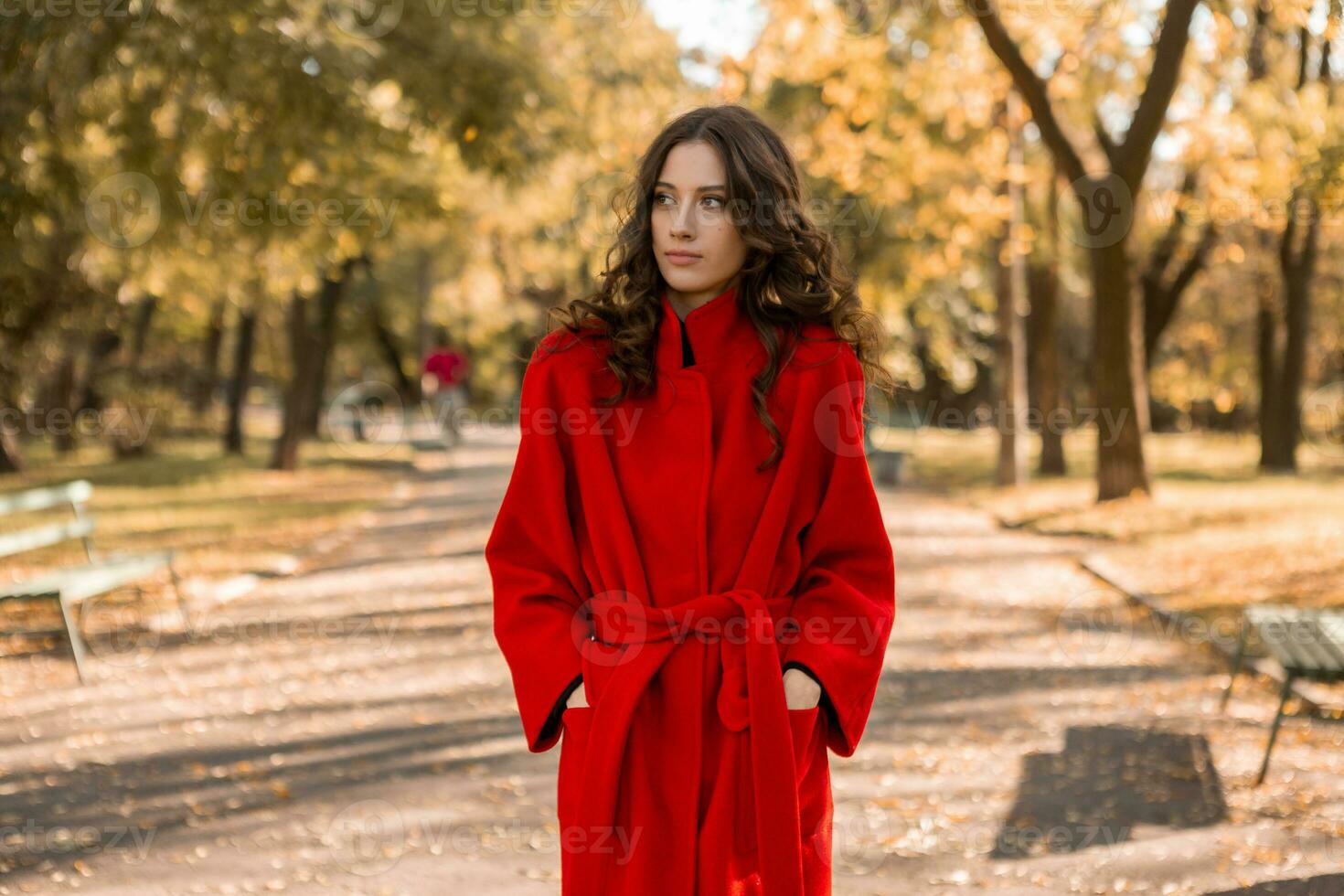 atractivo elegante mujer caminando en parque vestido en calentar rojo Saco foto