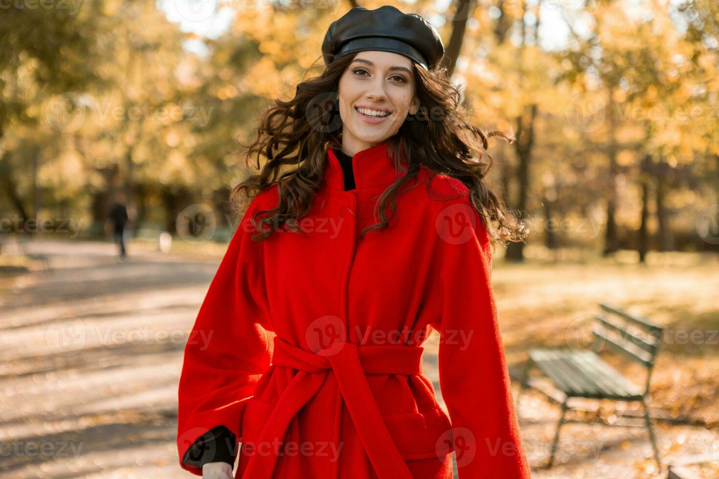 attractive stylish woman walking in park dressed in warm red coat photo