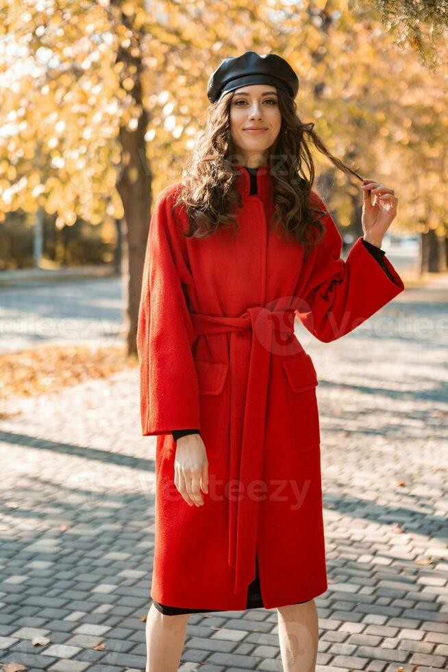 attractive stylish woman walking in park dressed in warm red coat photo