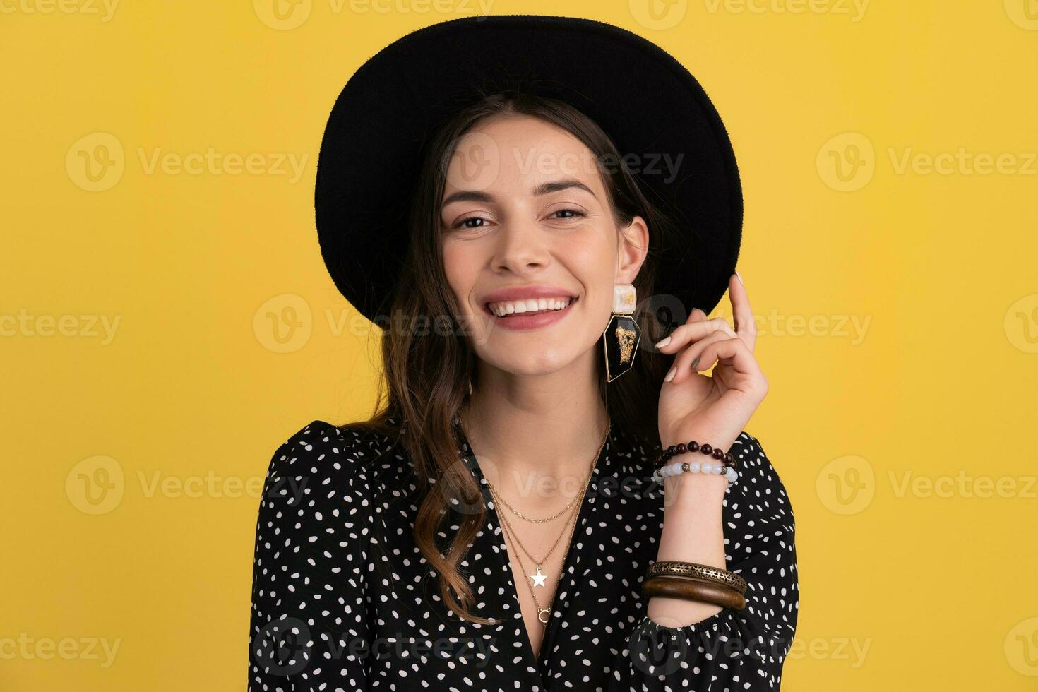 attractive woman posing isolated on yellow background wearing black hat and dress photo