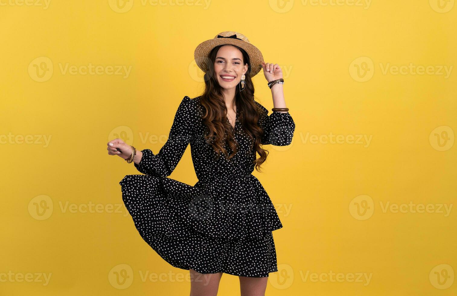 pretty woman posing isolated on yellow background wearing straw hat and dress photo