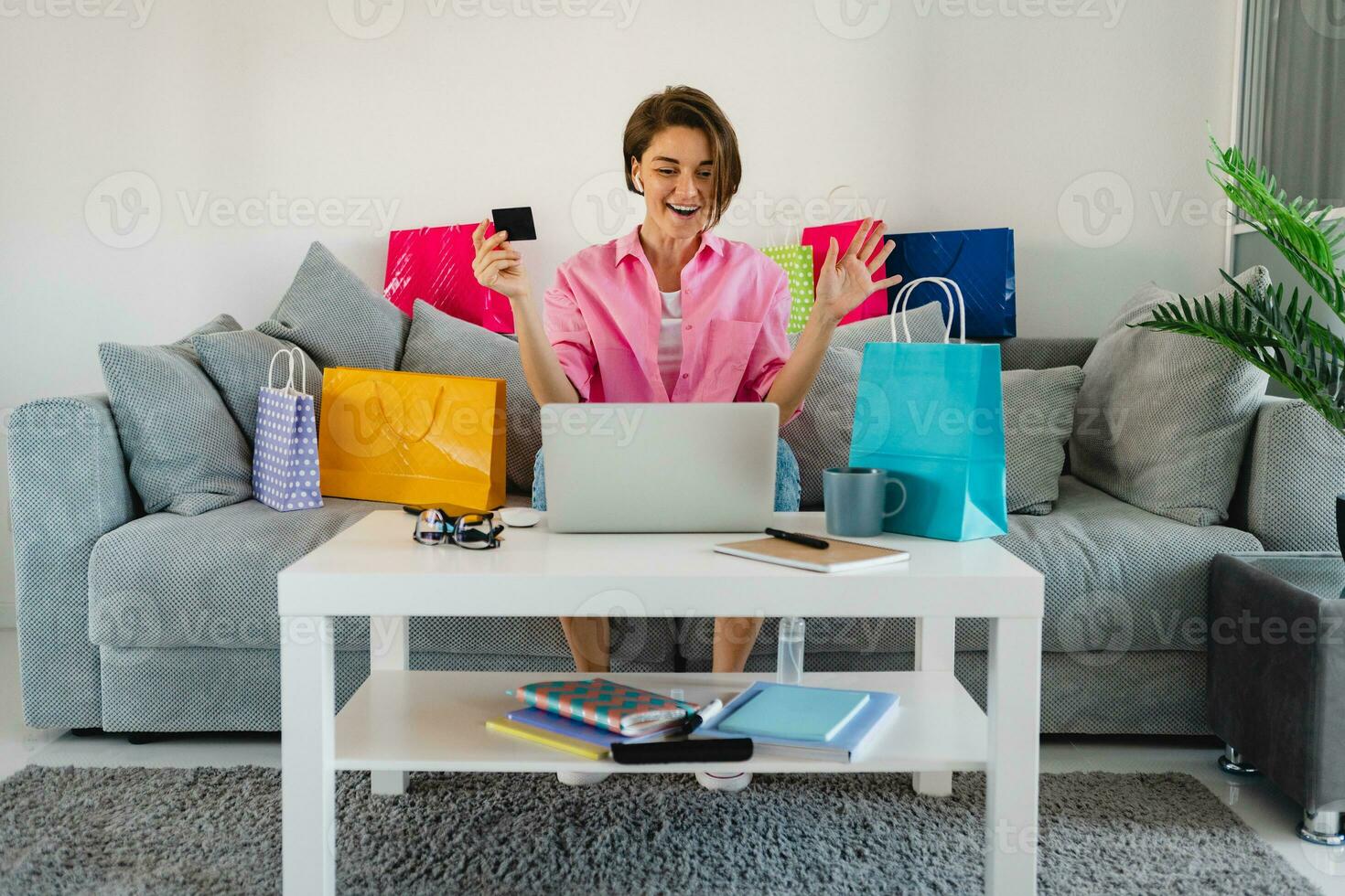 happy smiling woman in pink shirt on sofa at home shopping online photo