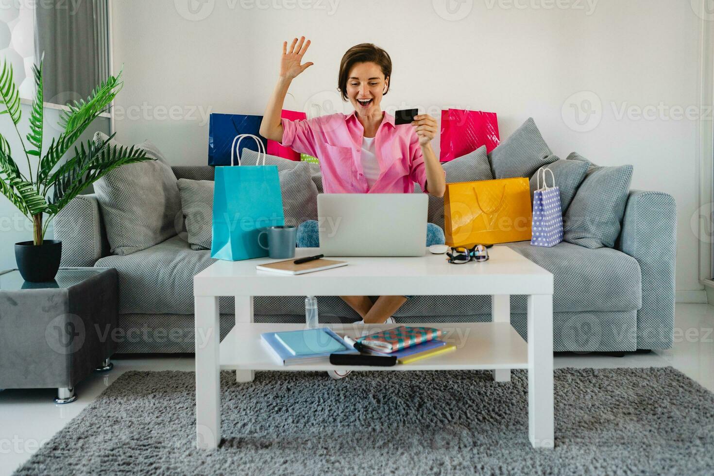 happy smiling woman in pink shirt on sofa at home shopping online photo