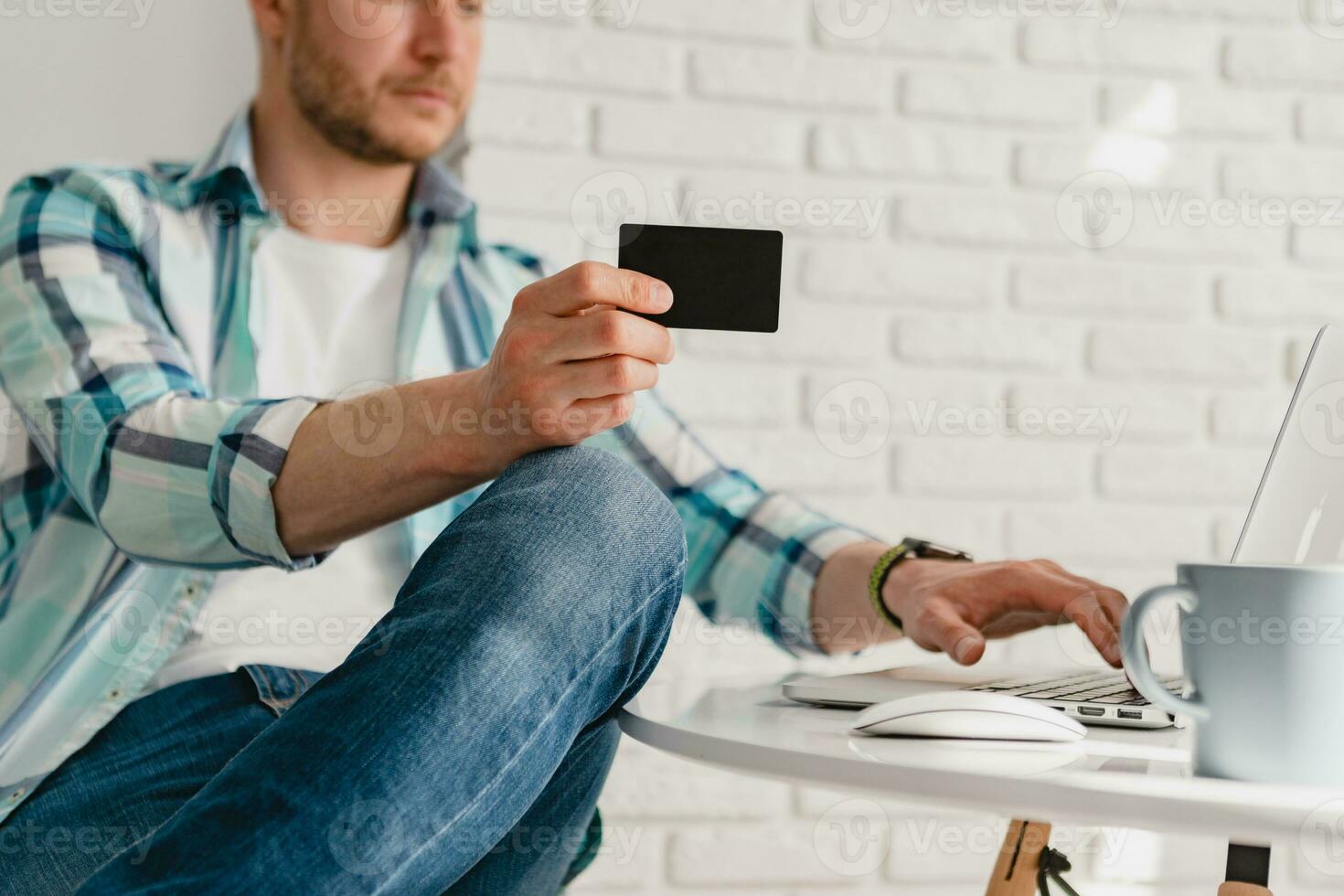 man in shirt sitting in kitchen at home at table working online on laptop photo