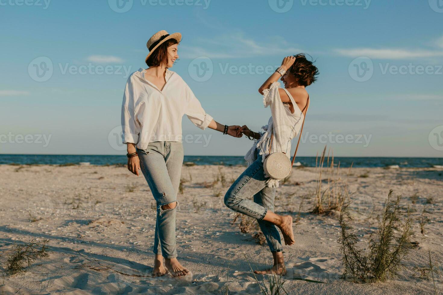 two young women having fun on the sunset beach photo