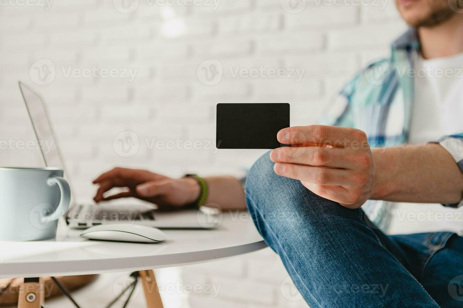 handsome smiling man in shirt sitting in kitchen at home at table working online on laptop photo