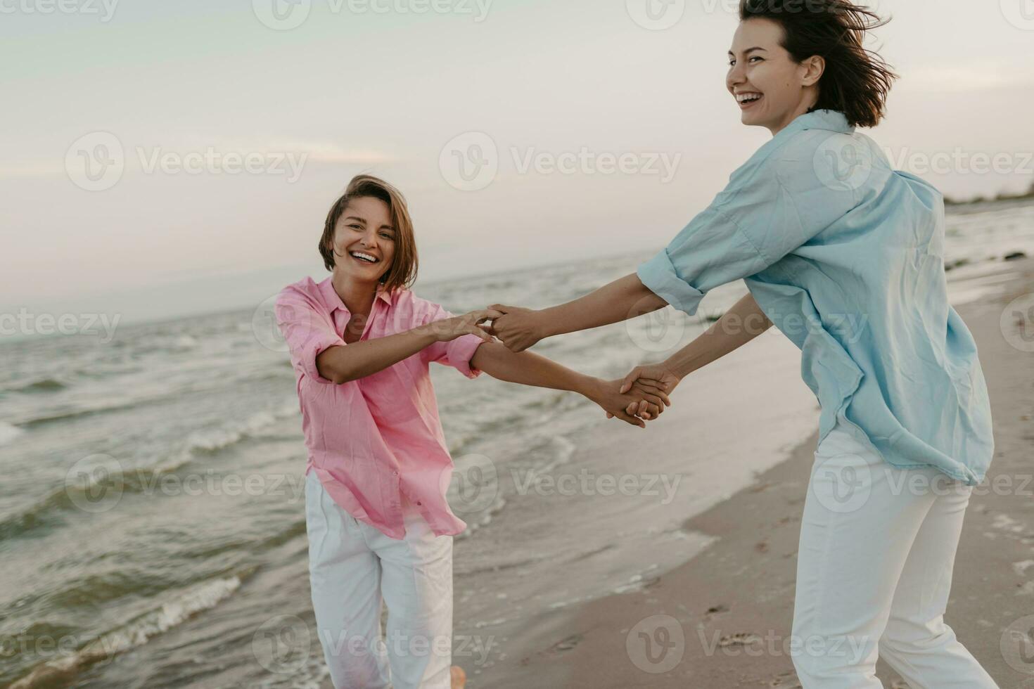 two young women having fun on the beach photo