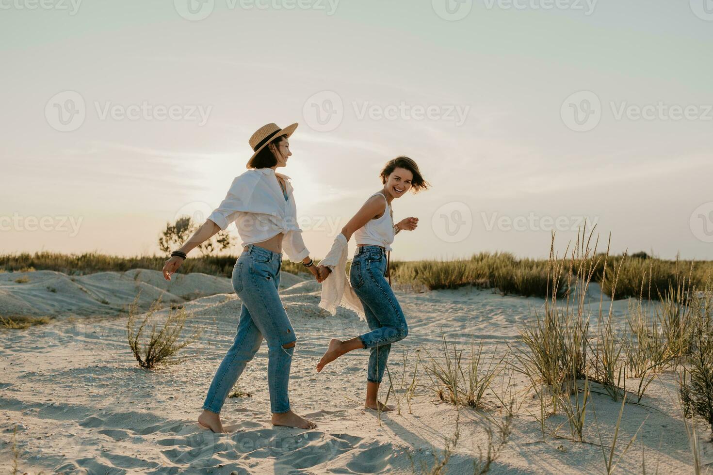 two young women having fun on the sunset beach photo
