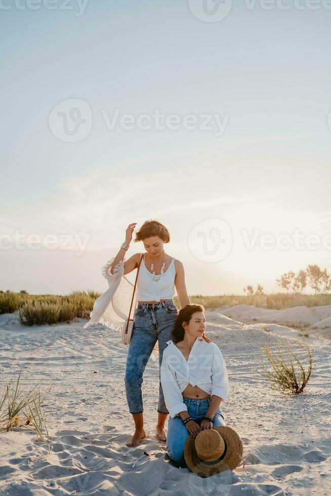 two young women having fun on the sunset beach photo