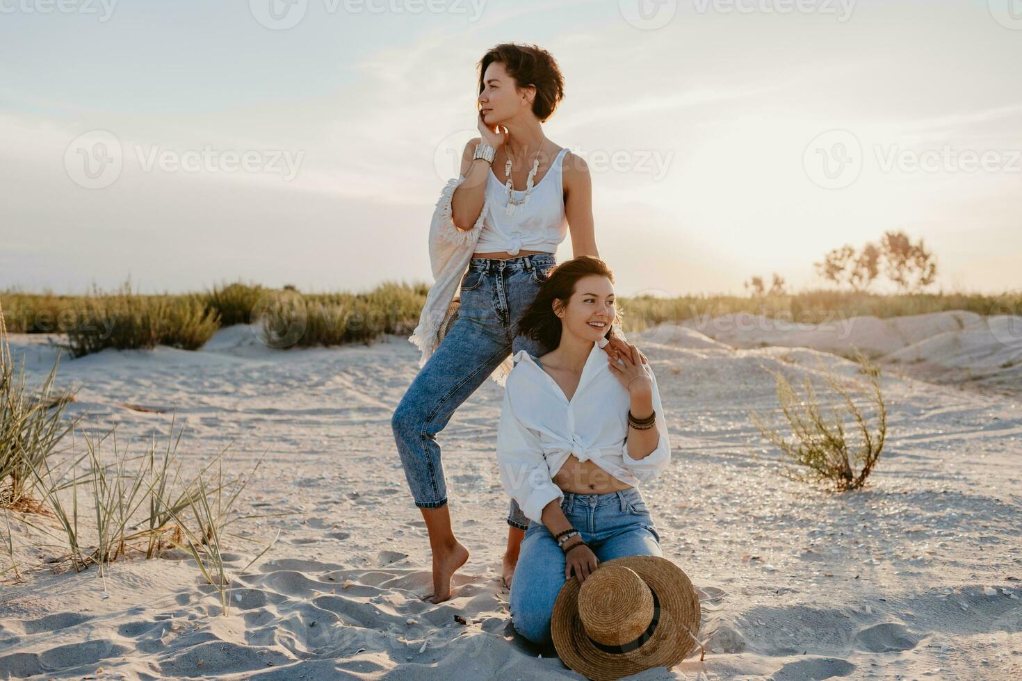 two young women having fun on the sunset beach photo