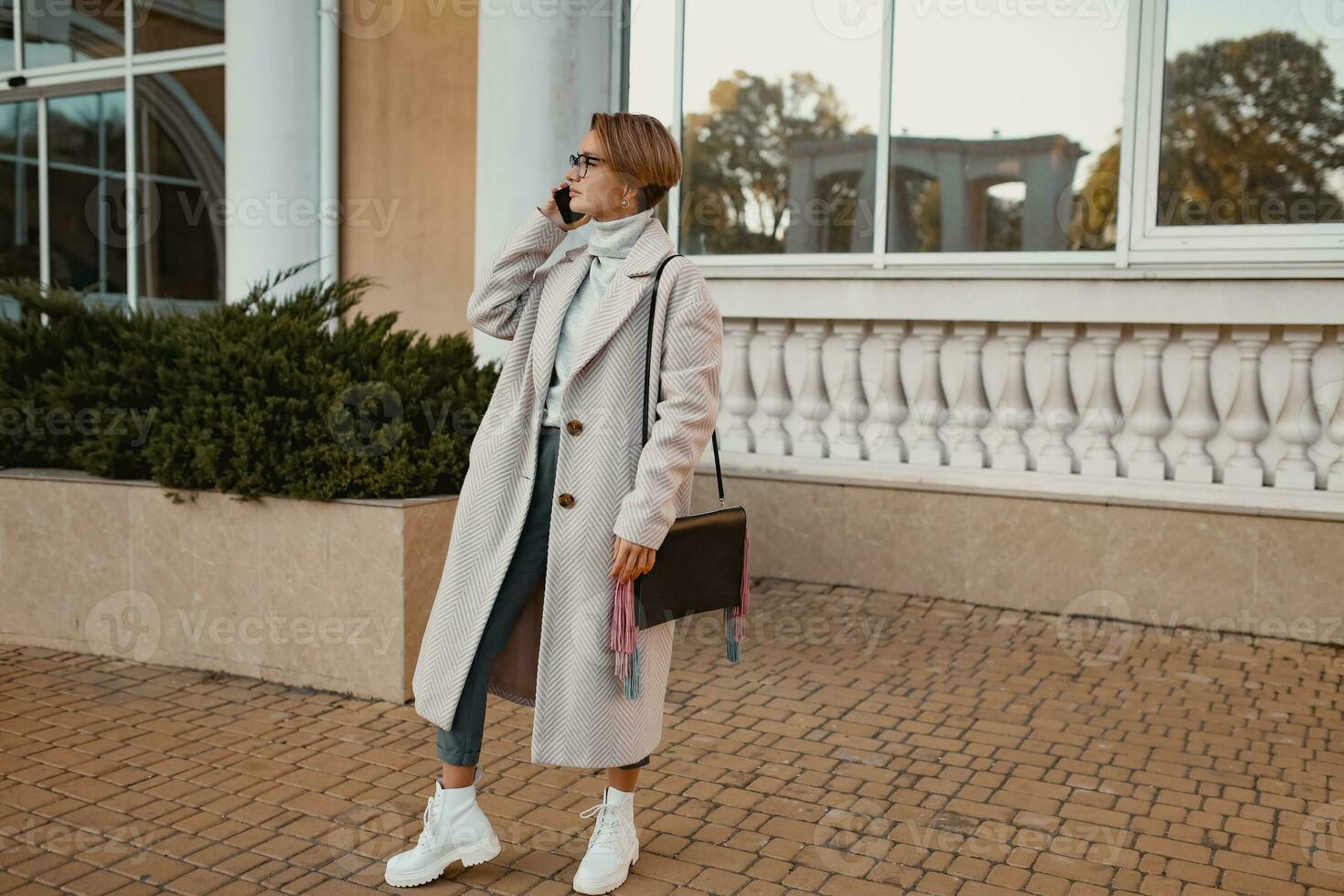 stylish fashionable woman walking in street in elegant style coat photo