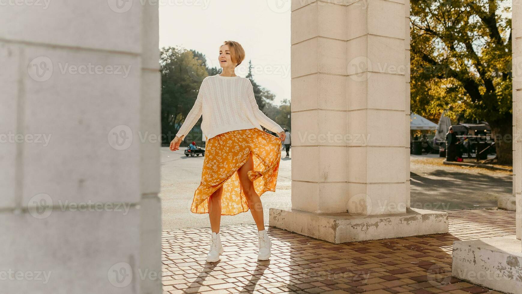 joven bonito contento sonriente mujer en amarillo impreso vestir y de punto blanco suéter foto