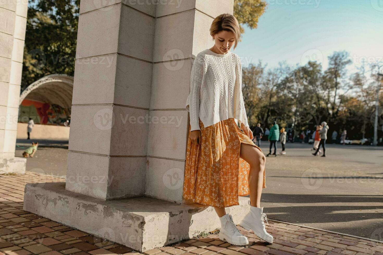 young pretty happy smiling woman in yellow printed dress and knitted white sweater photo