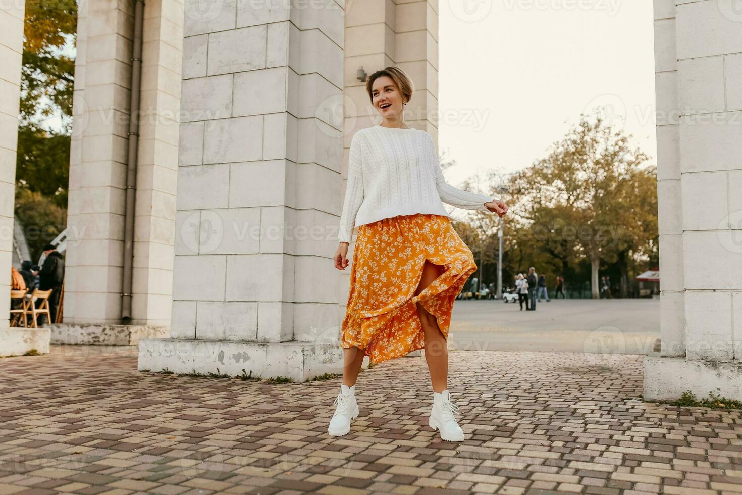 young pretty happy smiling woman in yellow printed dress and knitted white sweater photo