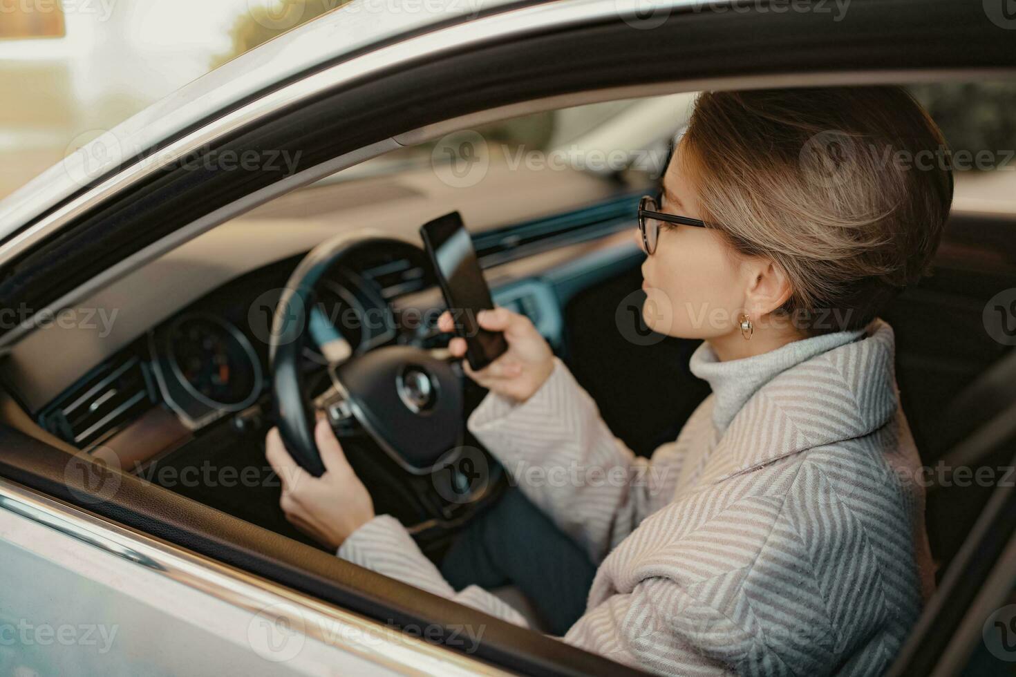 attractive stylish woman sitting in car dressed in coat photo