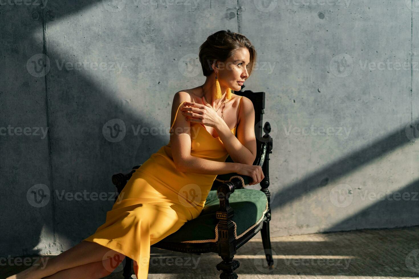 attractive woman in yellow summer dress in interior room concrete wall background photo