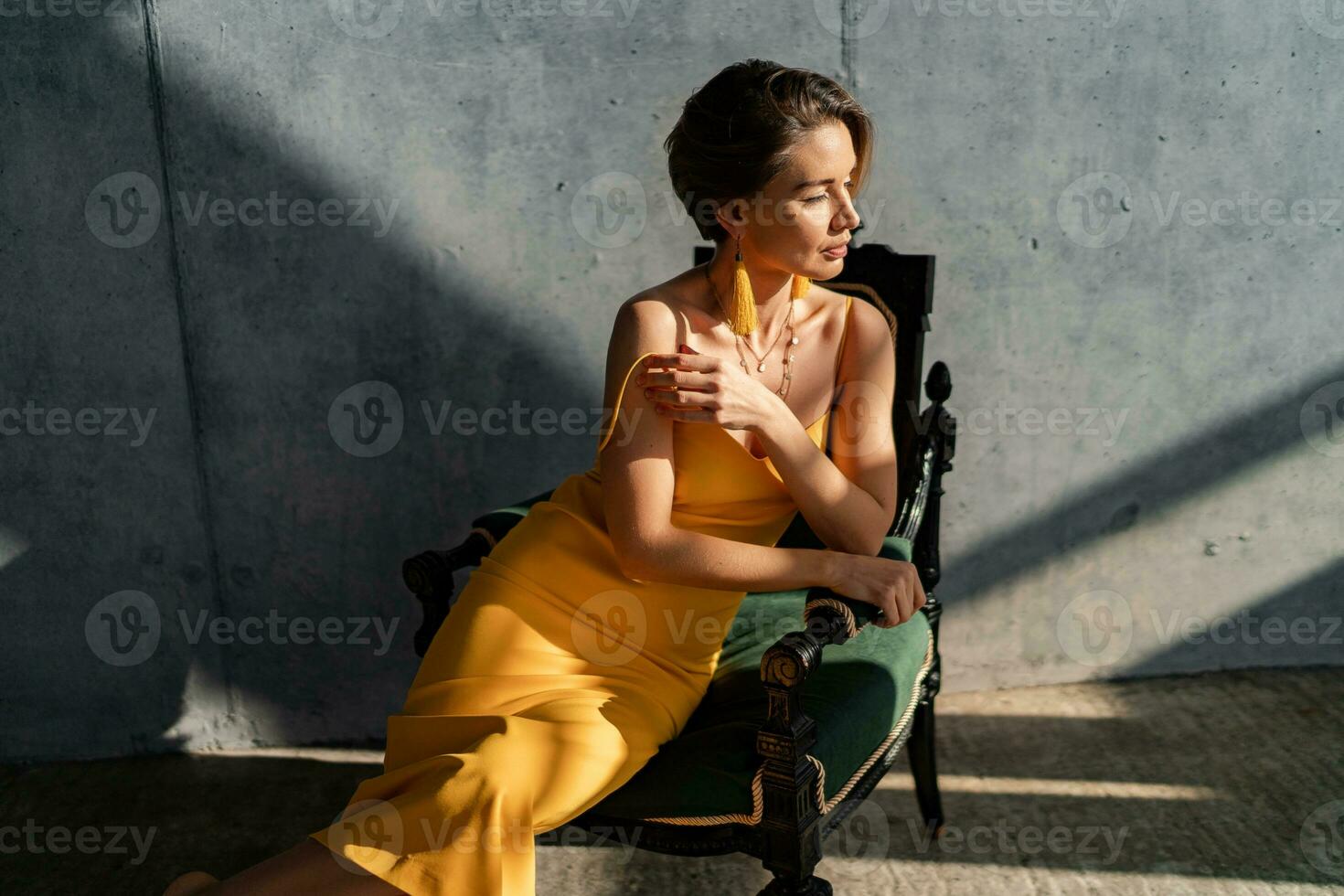 attractive woman in yellow summer dress in interior room concrete wall background photo