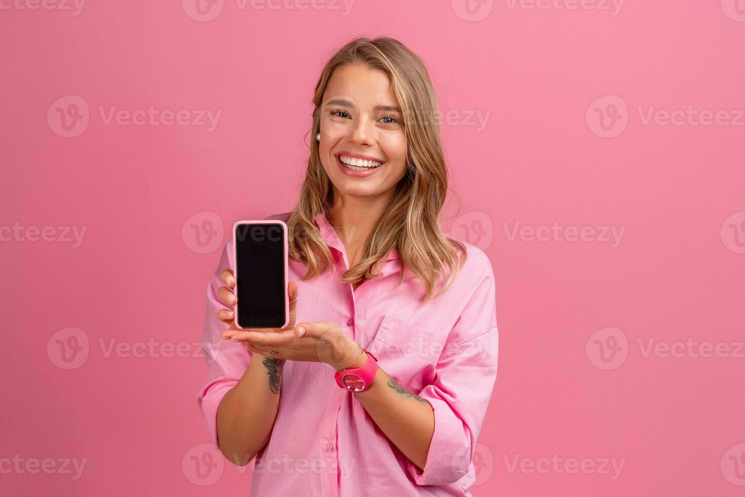 blond pretty woman in pink shirt smiling holding holding using smartphone photo