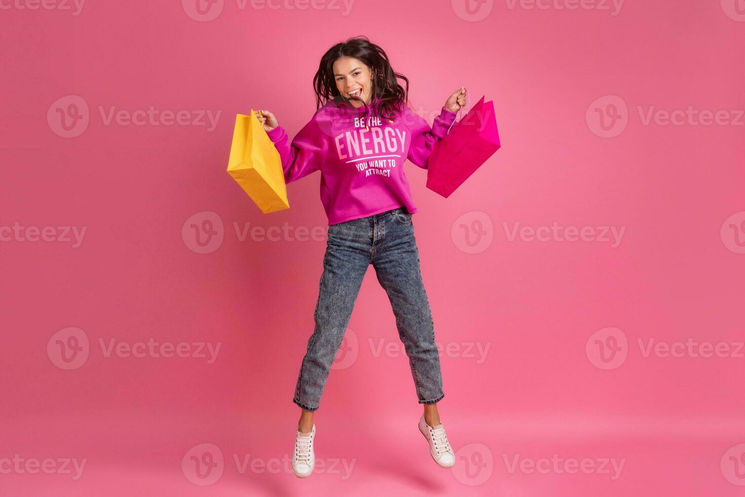 Hispano bonito mujer en rosado capucha sonriente saltando foto