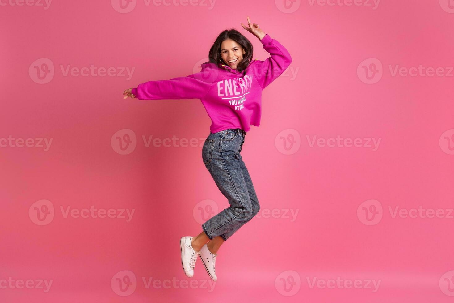 Hispano bonito mujer en rosado capucha sonriente saltando foto