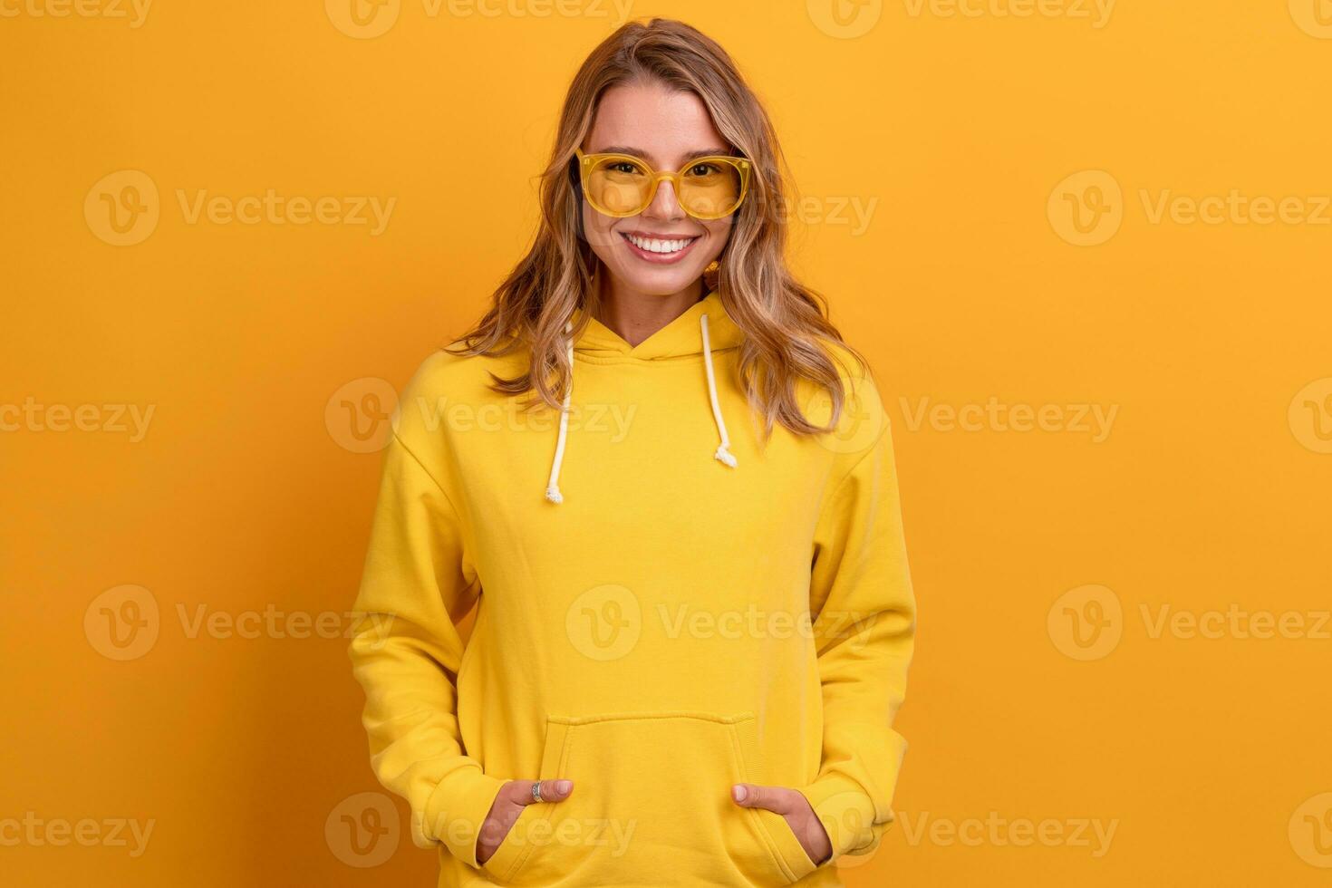 joven bonito rubia mujer linda cara expresión posando en amarillo capucha foto