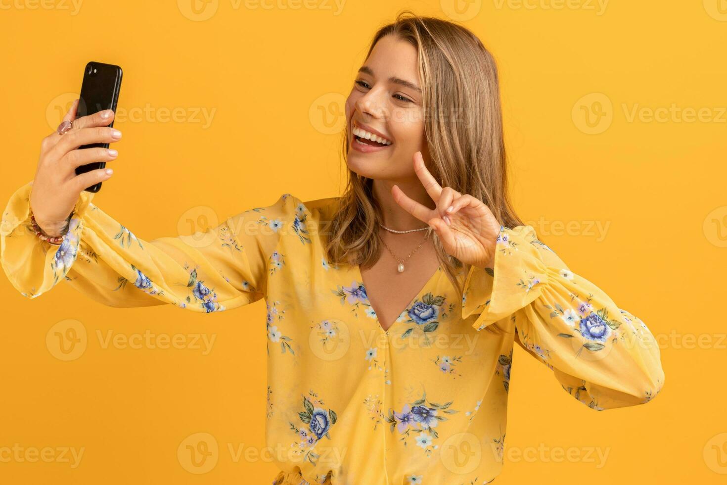 beautiful attractive smiling woman in yellow shirt holding smartphone photo