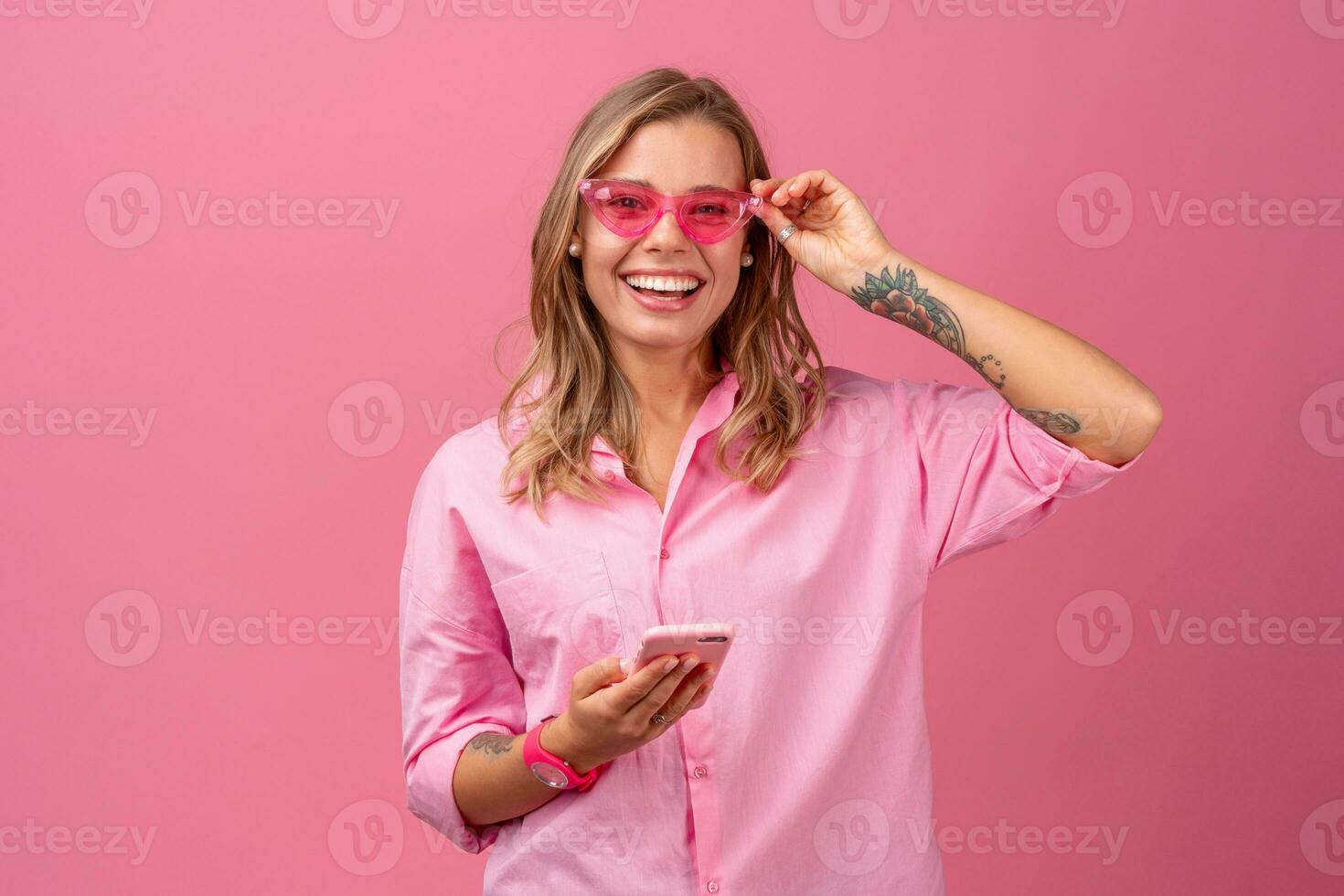 blond pretty woman in pink shirt smiling holding holding using smartphone photo