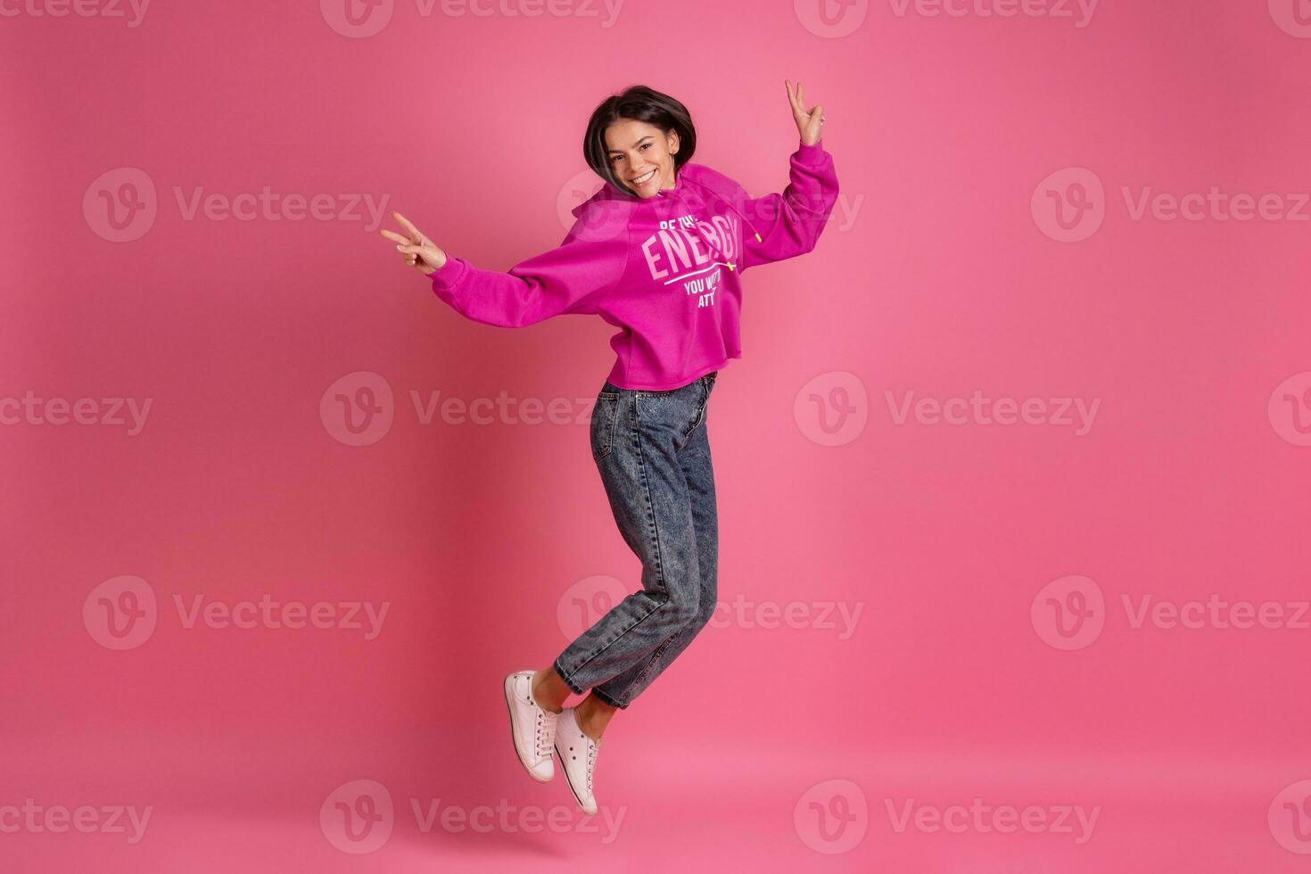 hispanic pretty woman in pink hoodie smiling jumping photo