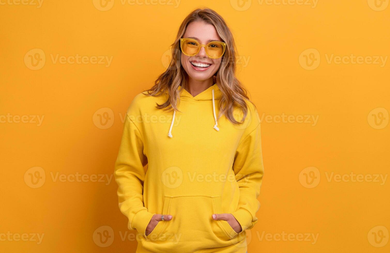 joven bonito rubia mujer linda cara expresión posando en amarillo capucha foto