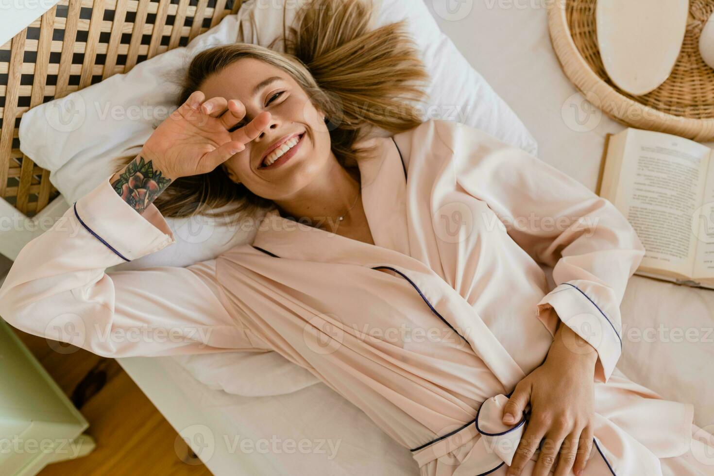 pretty smiling woman relaxing at home on bed in morning in pajamas photo