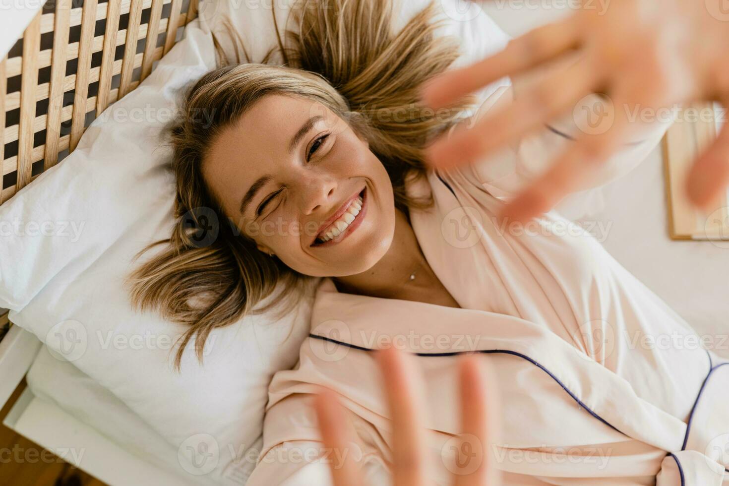 pretty smiling woman relaxing at home on bed in morning in pajamas photo