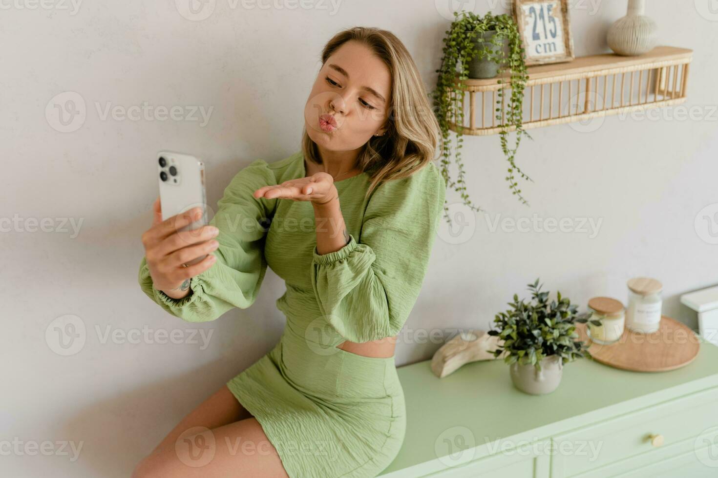 young stylish smiling woman in green summer dress in modern interior apartment home photo
