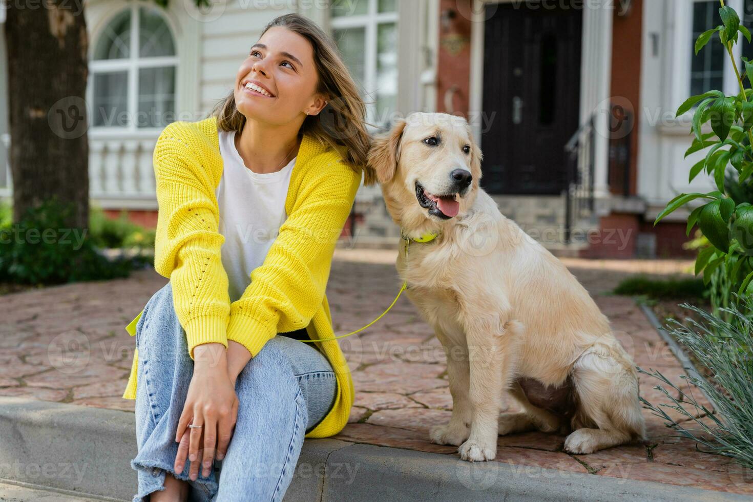 happy smiling woman in yellow sweater walking at her house with a dog golden retriever photo