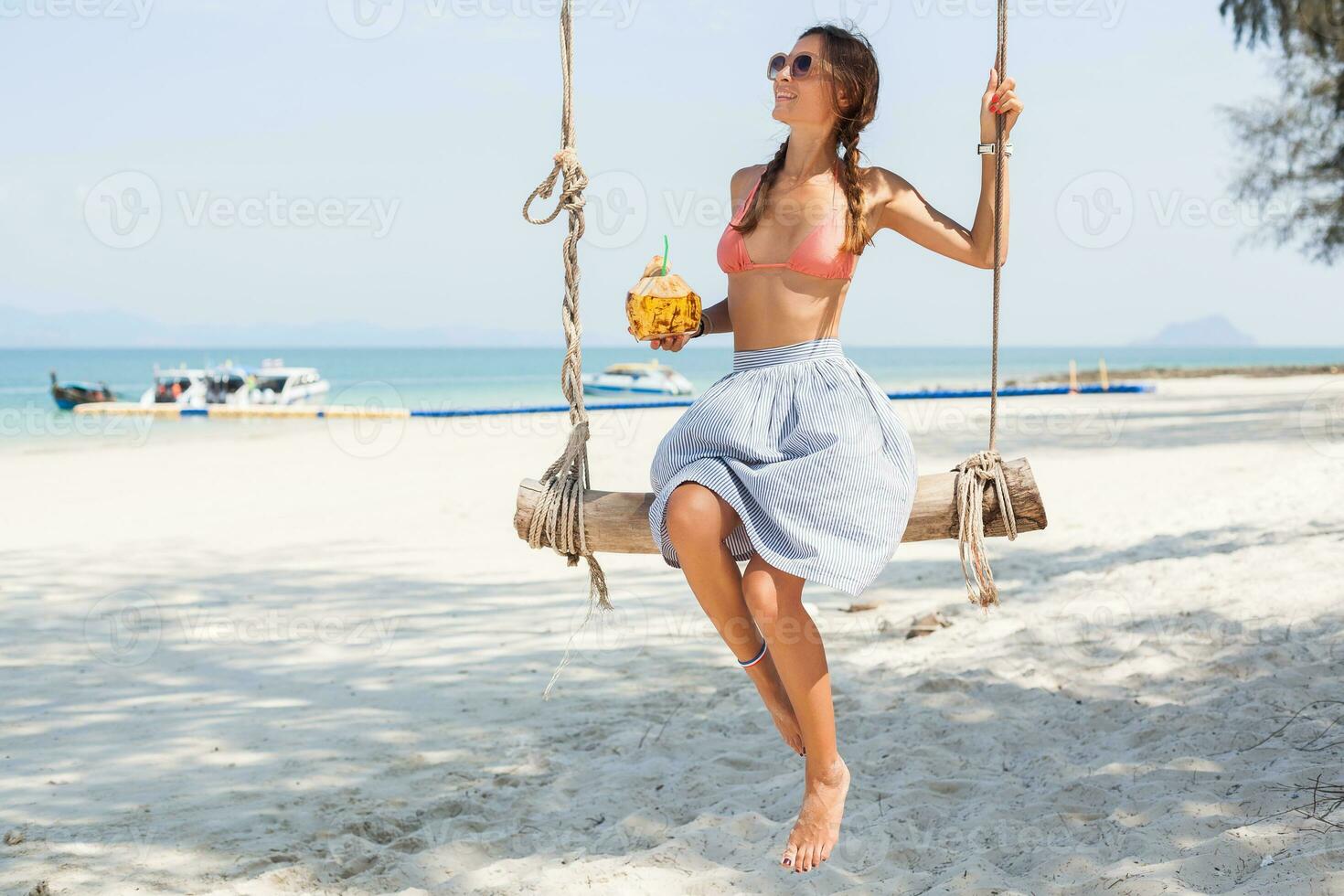 young sexy woman sitting on swing on tropical beach, summer vacation photo