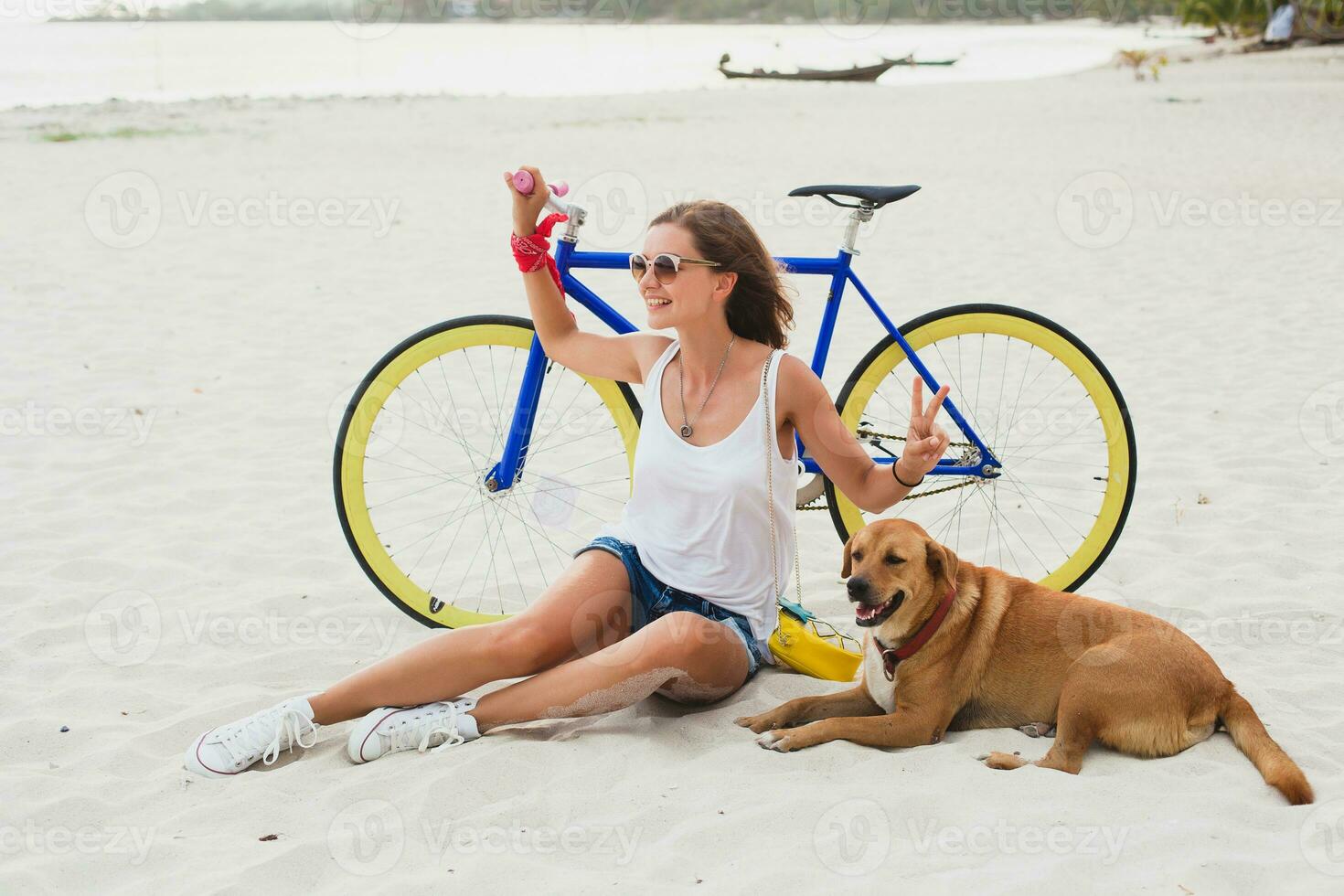 young beautiful woman sitting on sand on beach, holding vintage bicycle photo