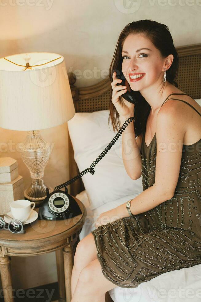 young beautiful woman sitting on bed in hotel room photo