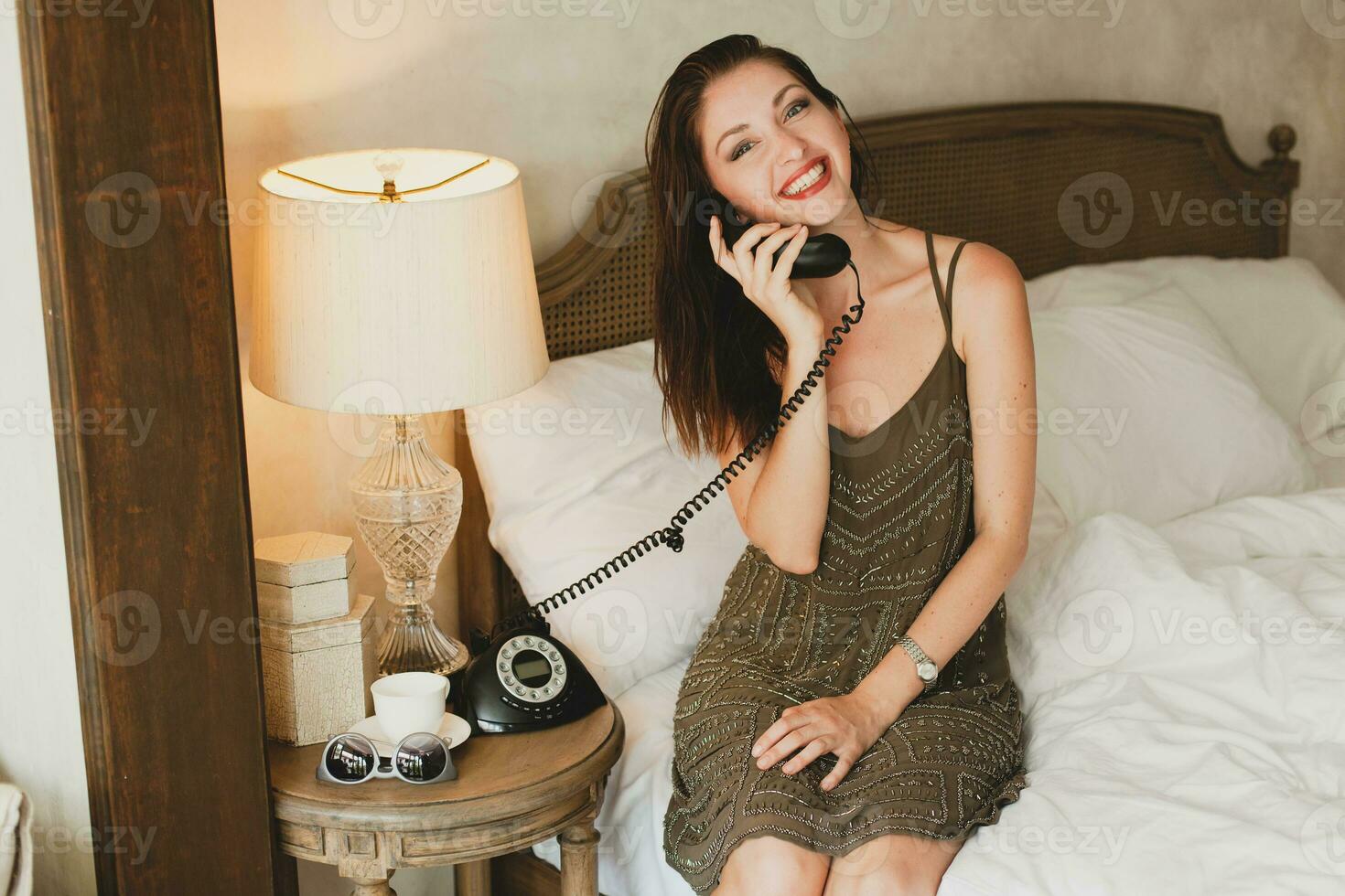 young beautiful woman sitting on bed in hotel room photo