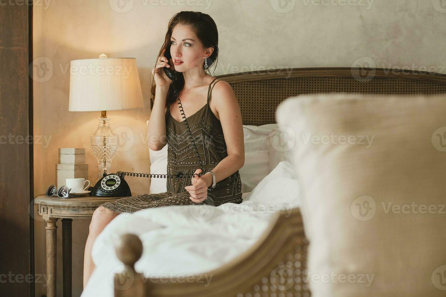 young beautiful woman sitting on bed in hotel room photo