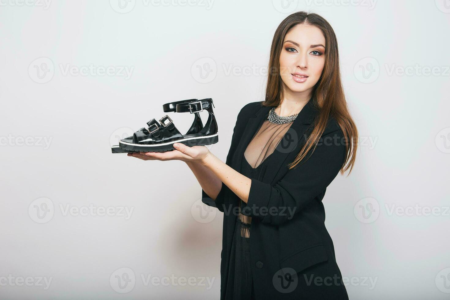 beautiful stylish woman isolated in black suit holding pait of shoes photo