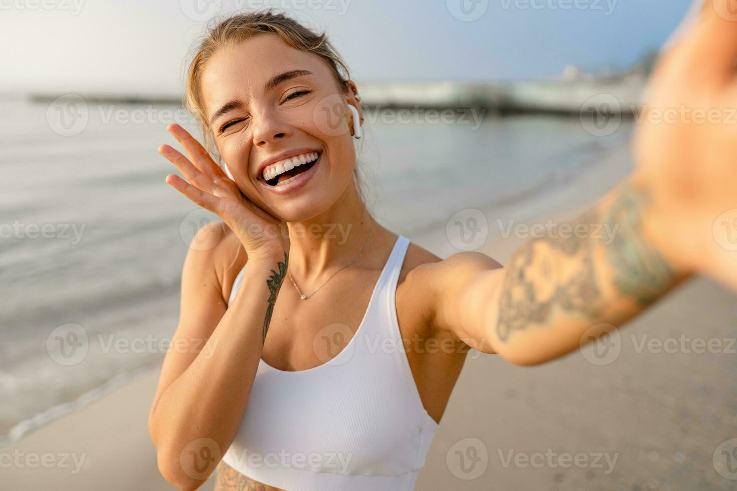 pretty young smiling woman doing sports in the morning in stylish sport outfit sportswear, taking selfie picture on smartphone camera photo