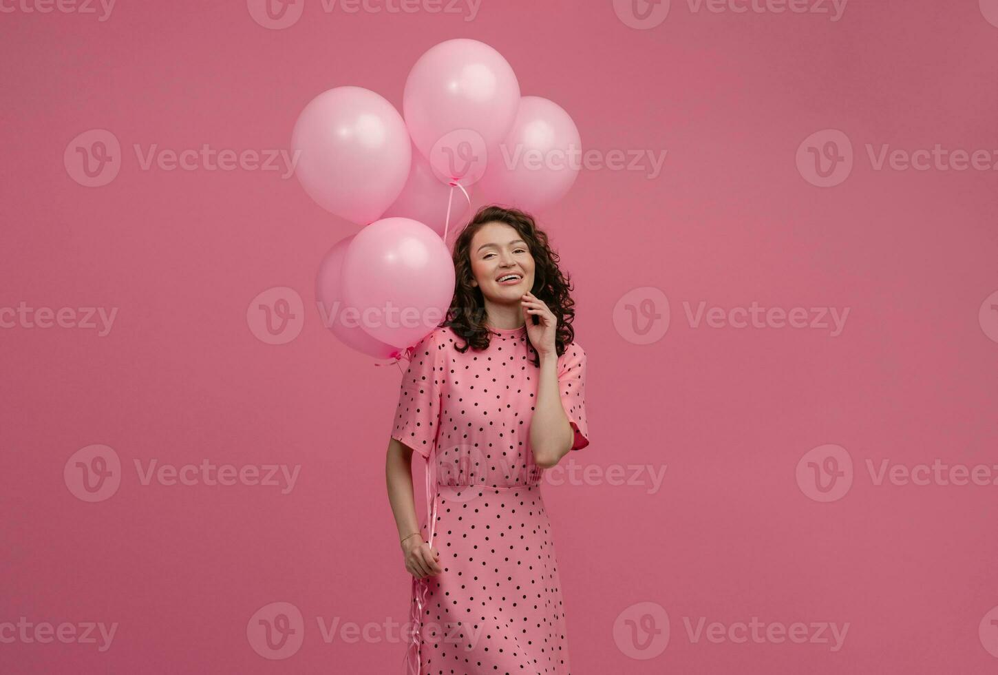 pretty young woman posing isolated on pink studio background with pink air baloons photo