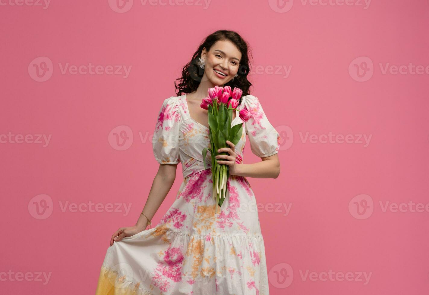 pretty young woman posing isolated on pink studio background with tulips flowers photo