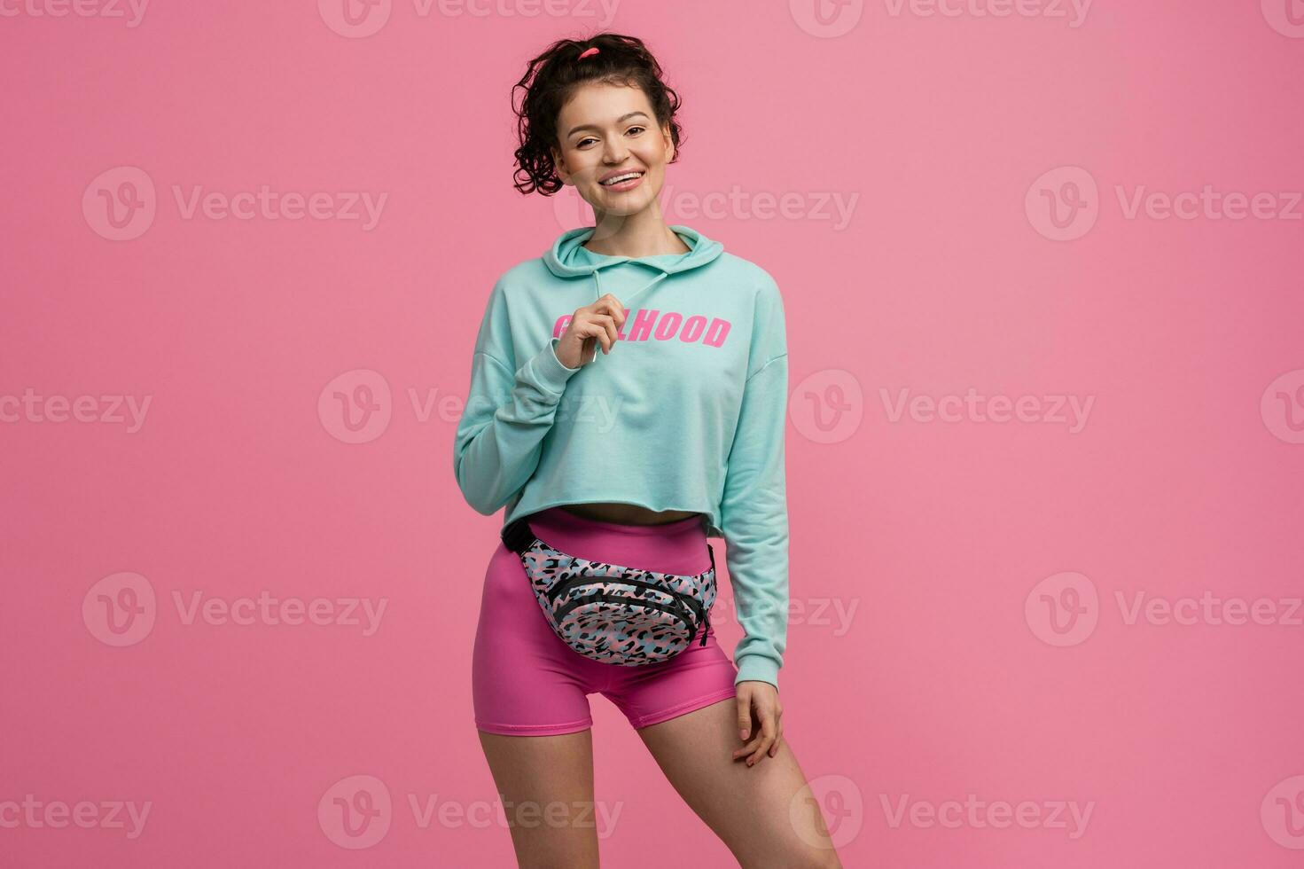 smiling happy beautiful woman in stylish sports outfit posing on pink background isolated in studio photo