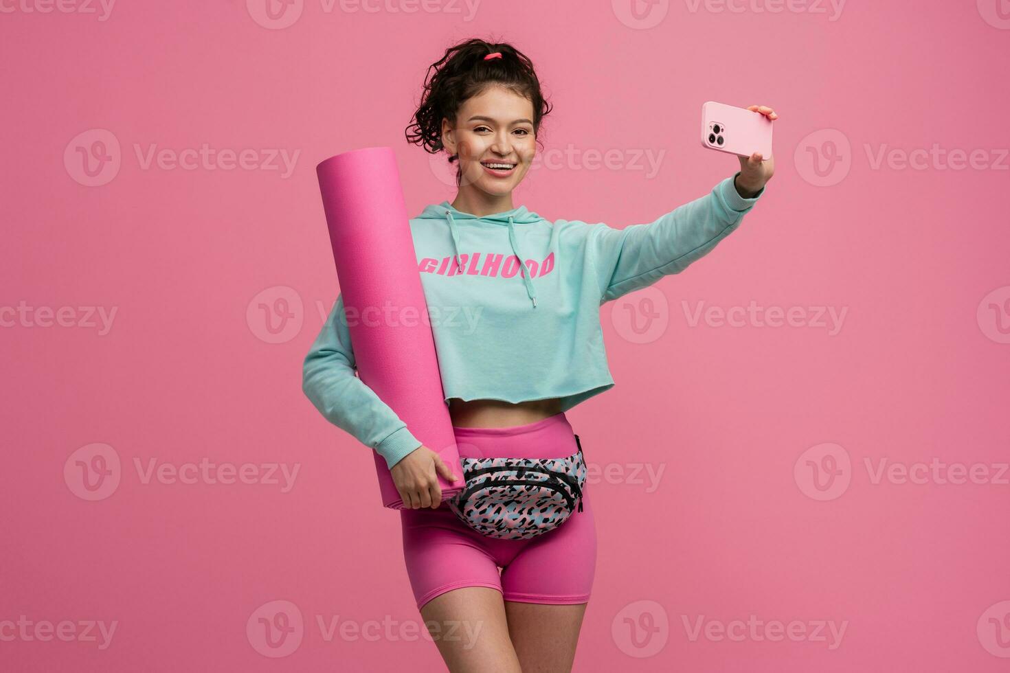 smiling happy beautiful woman in stylish sports outfit posing on pink background isolated in studio photo