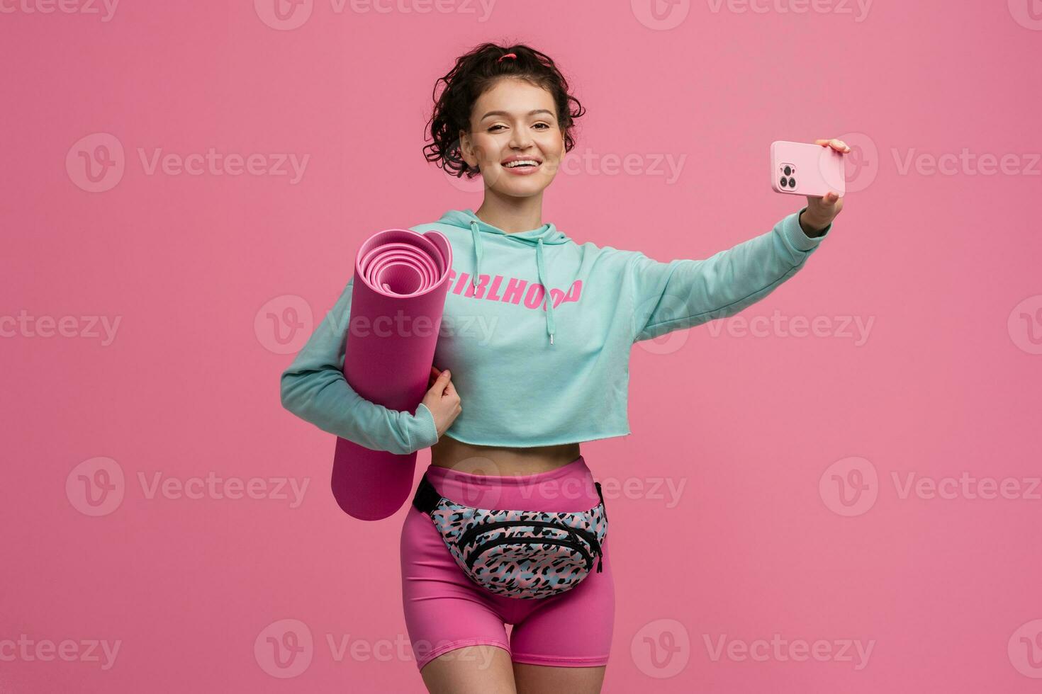 smiling happy beautiful woman in stylish sports outfit posing on pink background isolated in studio photo