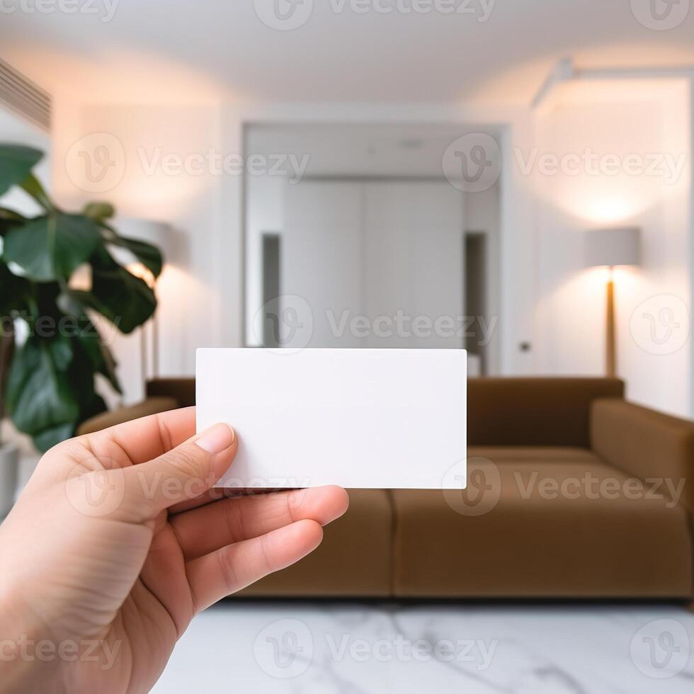 a hand holding a business card in front of a living room photo