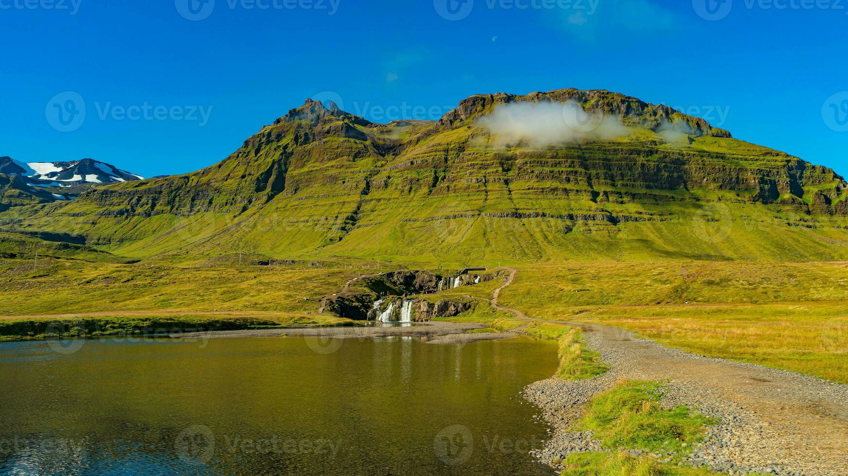 Wonderful waterfall named Kirkjufellsfoss with a Kirkjufell church like iconic mount in Western Iceland, at blue sky and sunny day photo