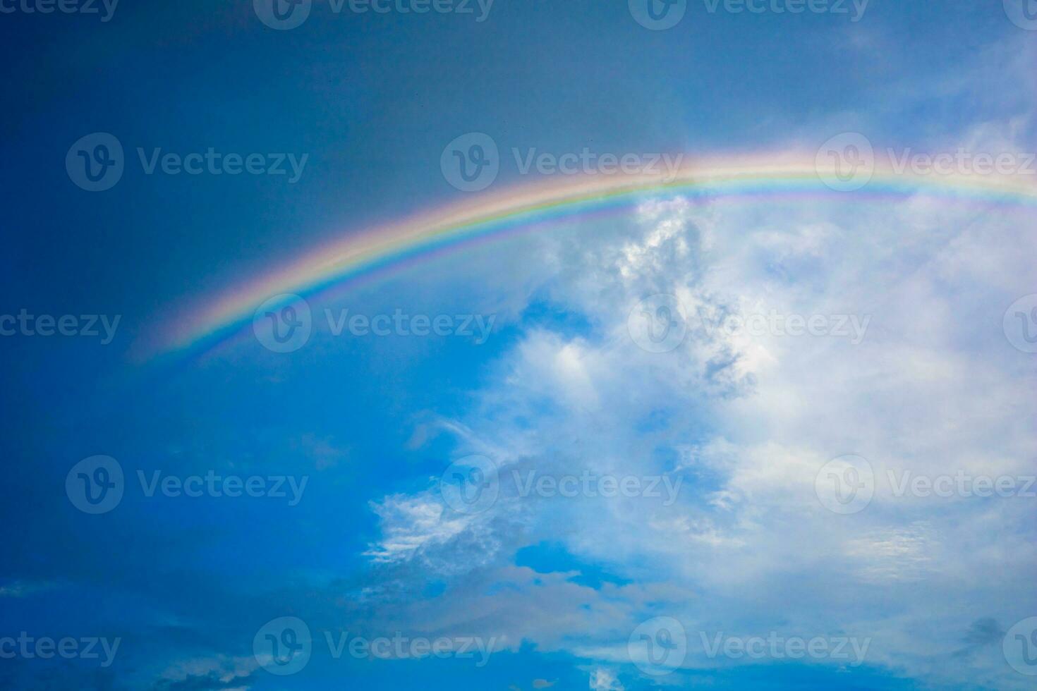 Beautiful multi-colored rainbow after rain on the blue sky and white clouds. photo