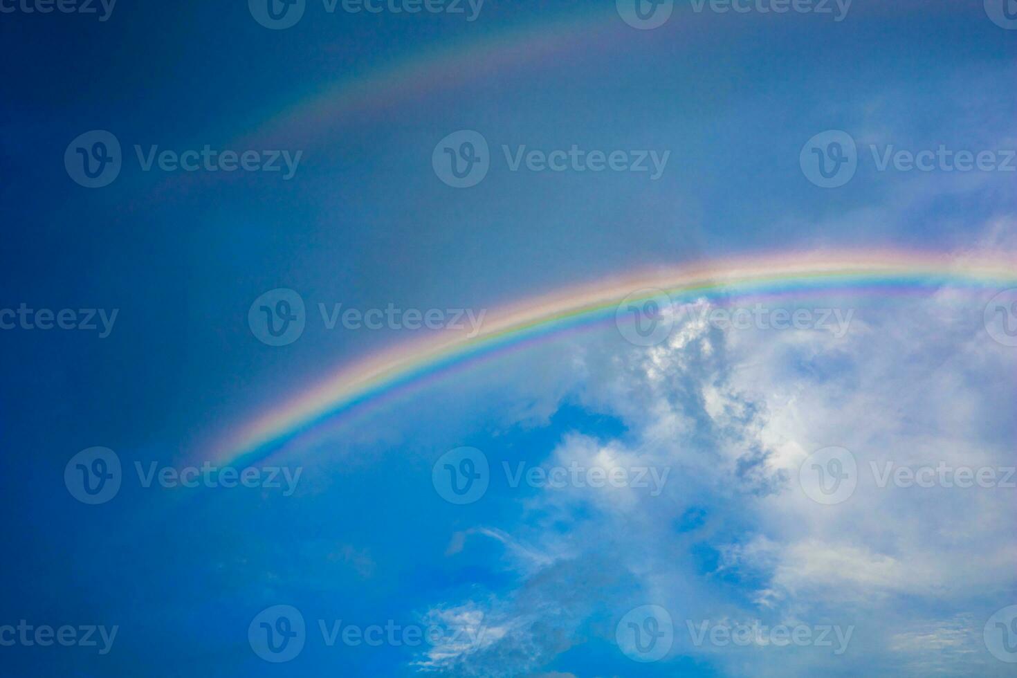 Beautiful multi-colored rainbow after rain on the blue sky and white clouds. photo